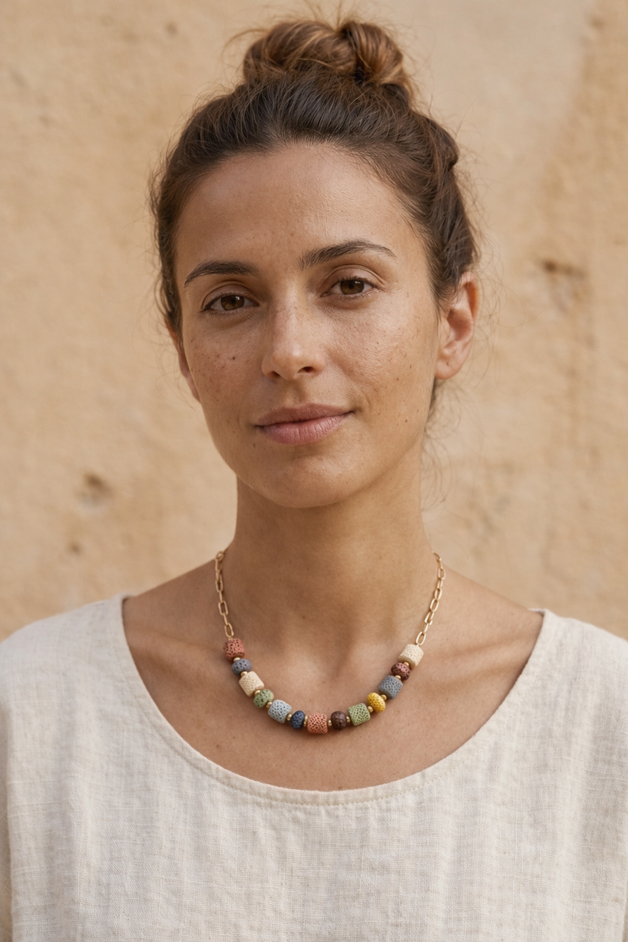Mujer con collar de piedras volcánicas multicolor y cadena dorada estilo natural y elegante