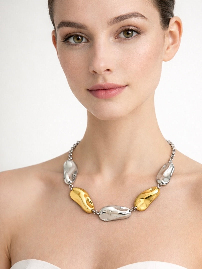 Mujer con collar Pebble bicolor de acero inoxidable en tonos dorado y plateado diseño orgánico elegante