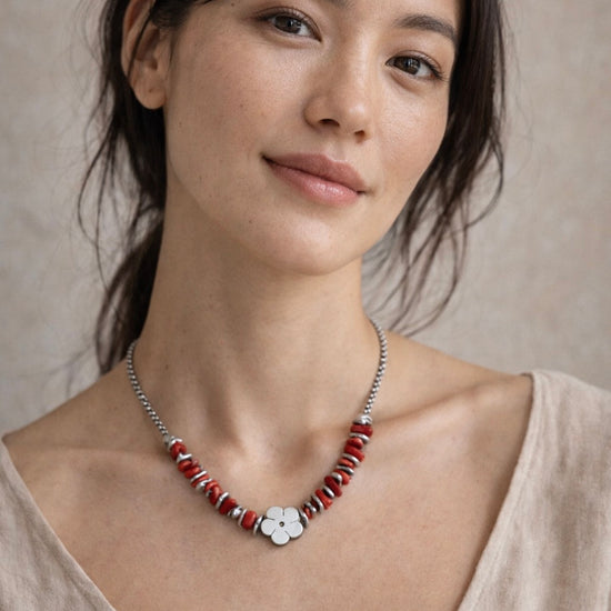Mujer con collar plateado con cuentas rojas y detalle de flor diseño elegante y moderno
