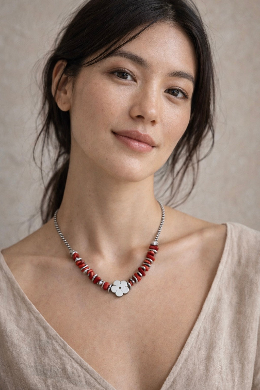 Mujer con collar plateado con cuentas rojas y detalle de flor diseño elegante y moderno