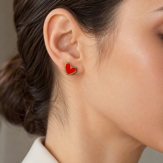 Mujer luciendo los Pendientes Corinne dorados con corazón rojo
