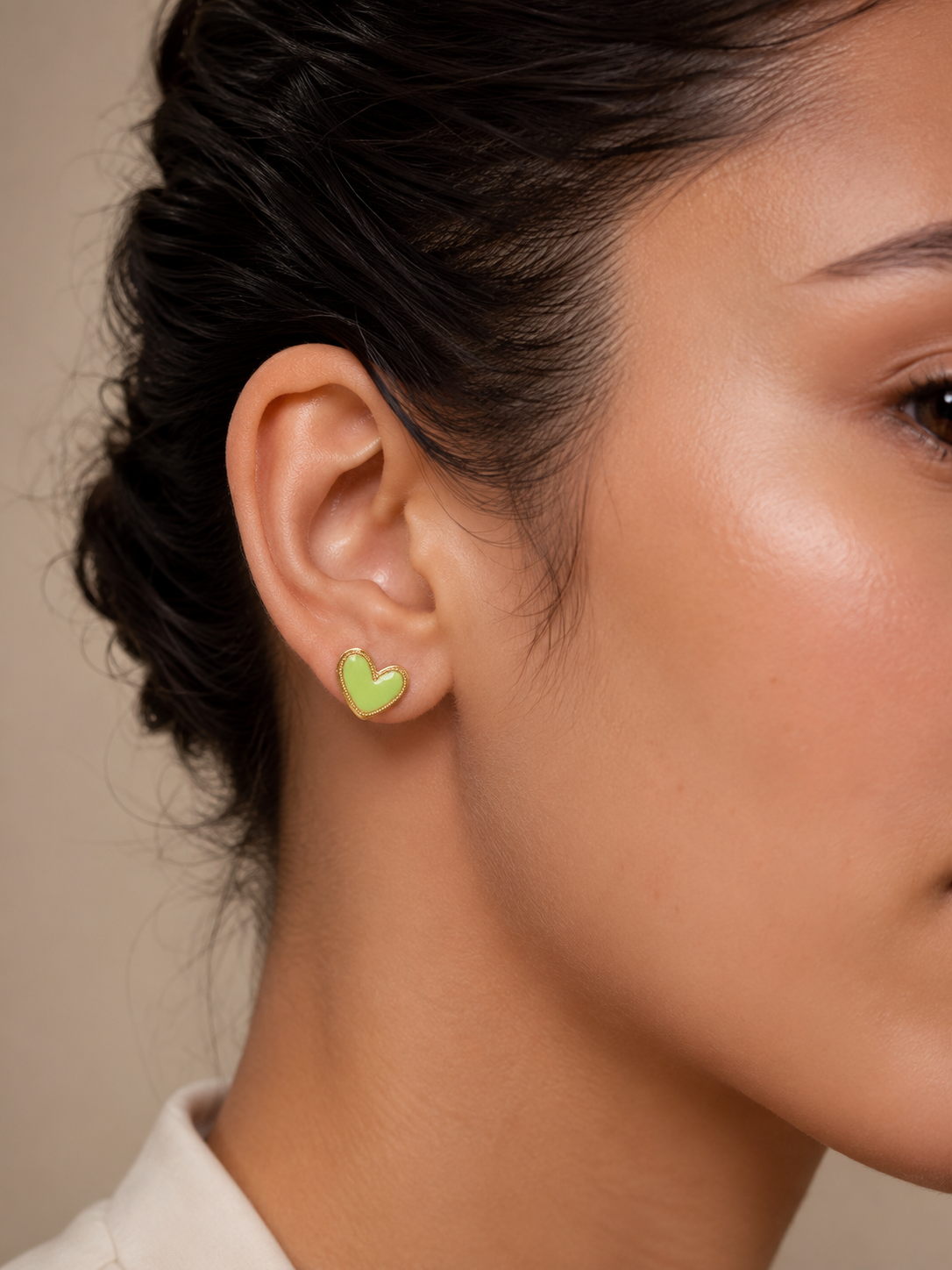 Mujer luciendo los Pendientes Corinne dorados con corazón verde lima