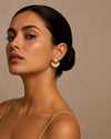 Mujer luciendo pendientes dorados geométricos semicirculares con detalle de nácar blanco, diseño elegante y moderno