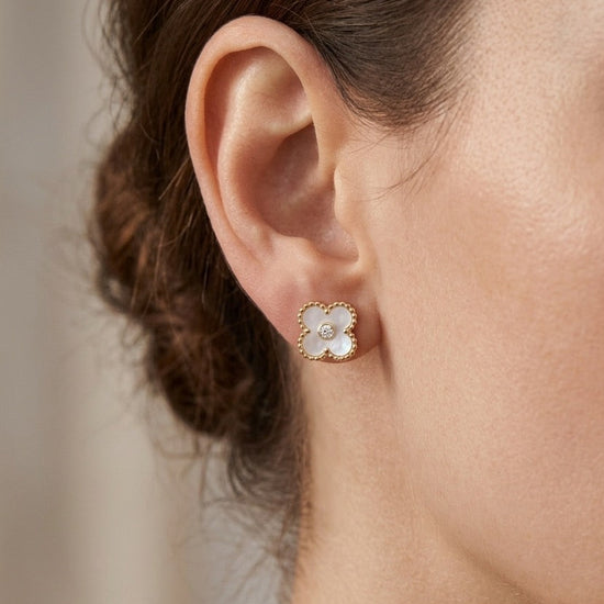 mujer llevando pendientes pequeños de flor blanca nacar con detalle dorado y circonita