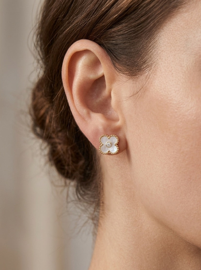 mujer llevando pendientes pequeños de flor blanca nacar con detalle dorado y circonita