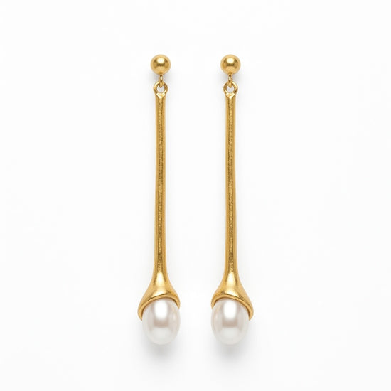 Pendientes largos dorados con perla blanca. Un diseño minimalista y elegante perfecto para looks sofisticados de día y noche.