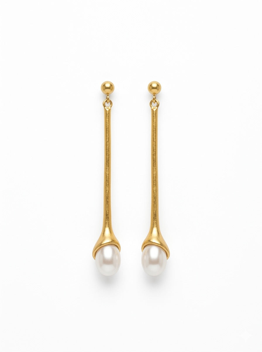 Pendientes largos dorados con perla blanca. Un diseño minimalista y elegante perfecto para looks sofisticados de día y noche.