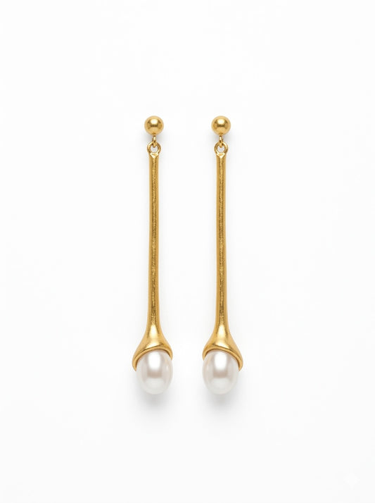 Pendientes largos dorados con perla blanca. Un diseño minimalista y elegante perfecto para looks sofisticados de día y noche.