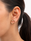 Mujer luciendo los Pendientes Lyssa dorados con diseño de corazón abierto