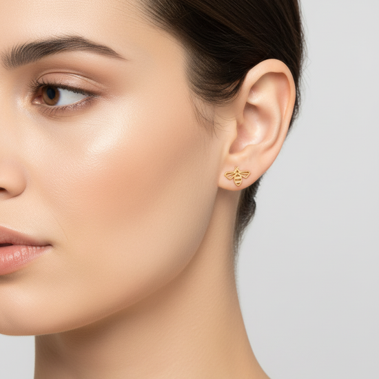 Pendientes mini dorados con silueta de abeja calada (modelo Abeja Mini) sobre modelo