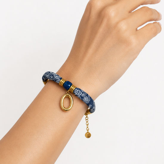 Modelo llevando la Pulsera Amalfi azul de tejido estampado con detalle central azul y colgante ovalado dorado de BRAVATA.