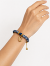 Modelo llevando la Pulsera Amalfi azul de tejido estampado con detalle central azul y colgante ovalado dorado de BRAVATA.