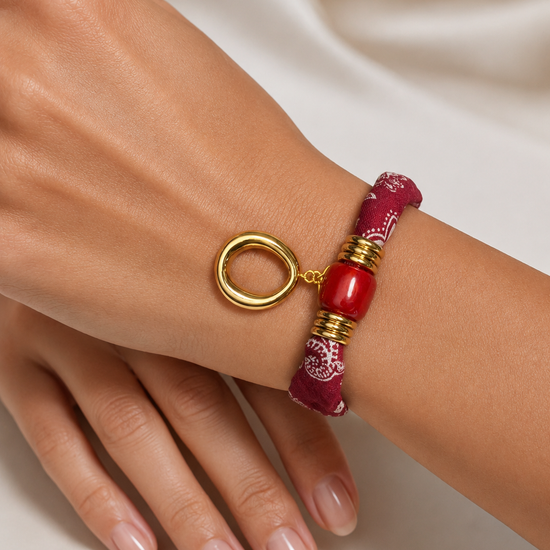 Modelo llevando la Pulsera Amalfi roja de tejido estampado con detalle central rojo y colgante ovalado dorado de BRAVATA.