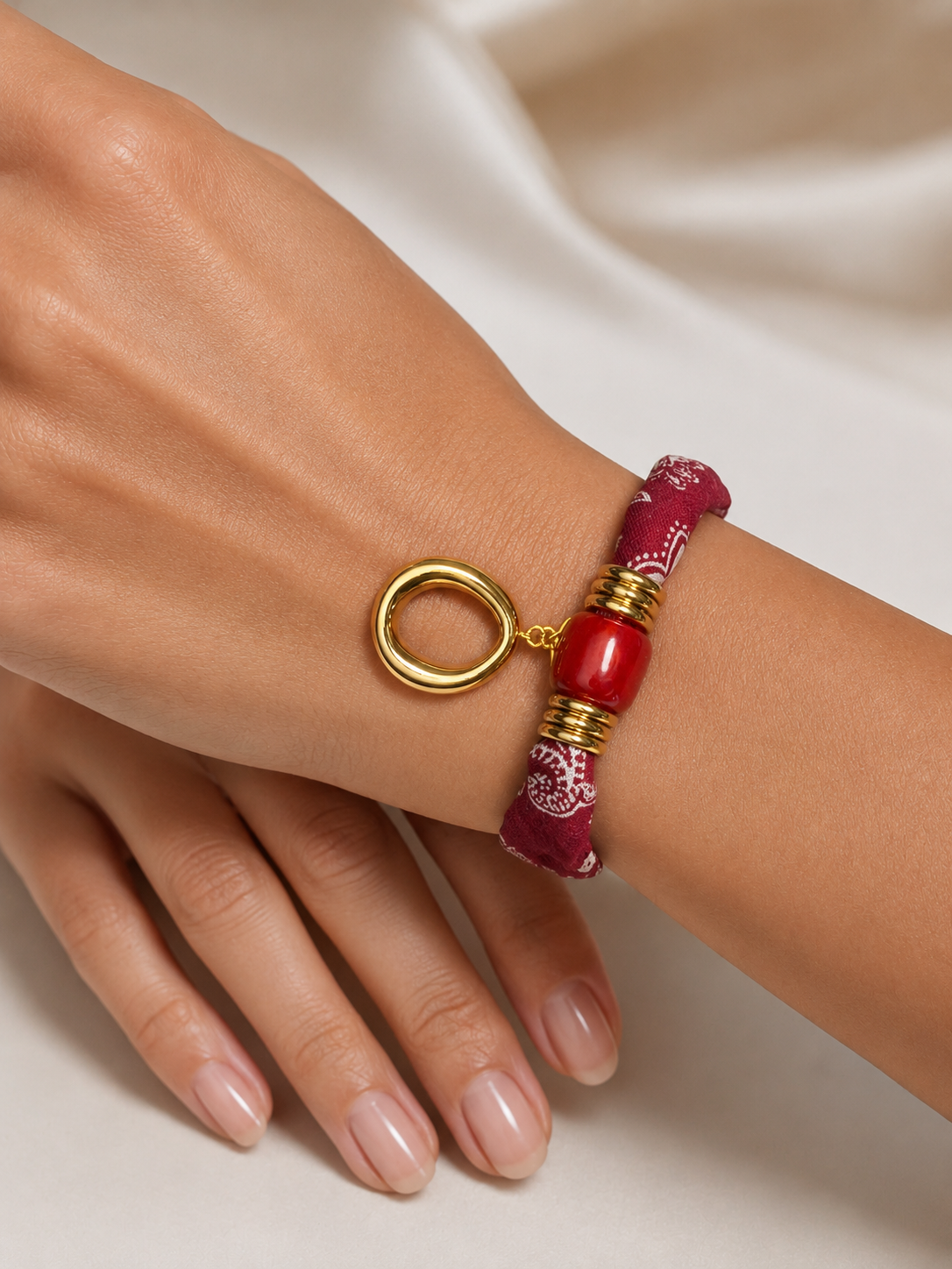 Modelo llevando la Pulsera Amalfi roja de tejido estampado con detalle central rojo y colgante ovalado dorado de BRAVATA.
