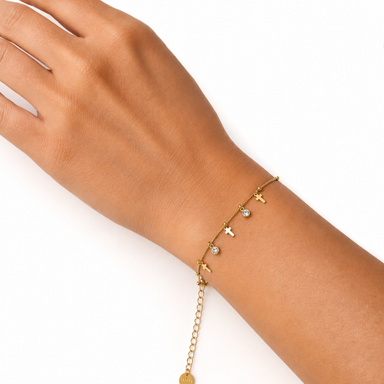 Modelo llevando la Pulsera Celeste dorada con cruces colgantes y circonitas blancas de BRAVATA.