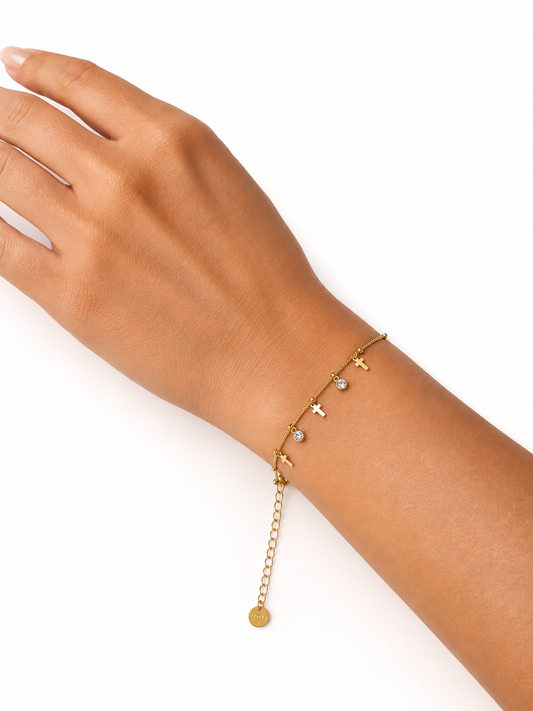 Modelo llevando la Pulsera Celeste dorada con cruces colgantes y circonitas blancas de BRAVATA.