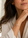 Mujer llevando pulsera dorada ajustable con circonita brillante de BRAVATA