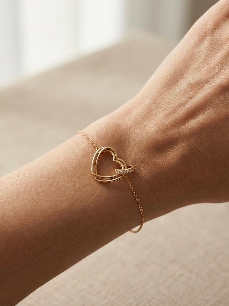 Pulsera de corazón dorada en muñeca femenina elegante
