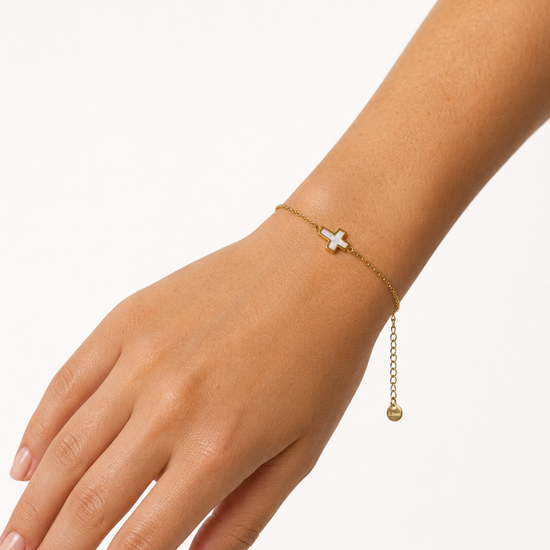 Modelo llevando la Pulsera Cruz dorada con motivo de cruz blanca nacarada de BRAVATA.