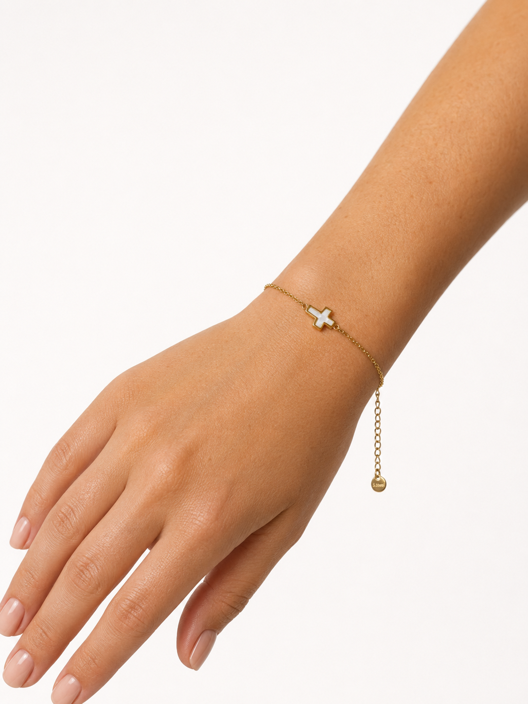 Modelo llevando la Pulsera Cruz dorada con motivo de cruz blanca nacarada de BRAVATA.