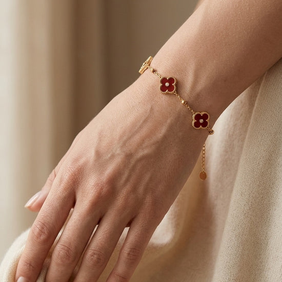 Pulsera dorada con flores rojas en muñeca mujer elegante