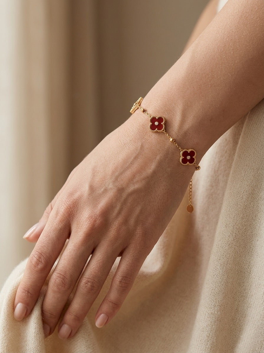 Pulsera dorada con flores rojas en muñeca mujer elegante