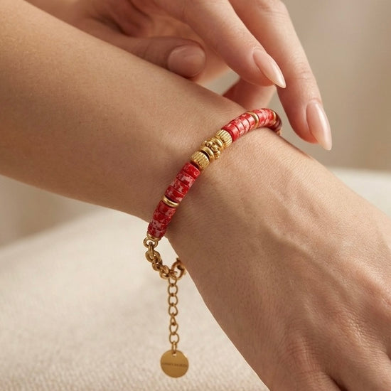mujer llevando pulsera dorada con cuentas rojas en la muñeca estilo moderno