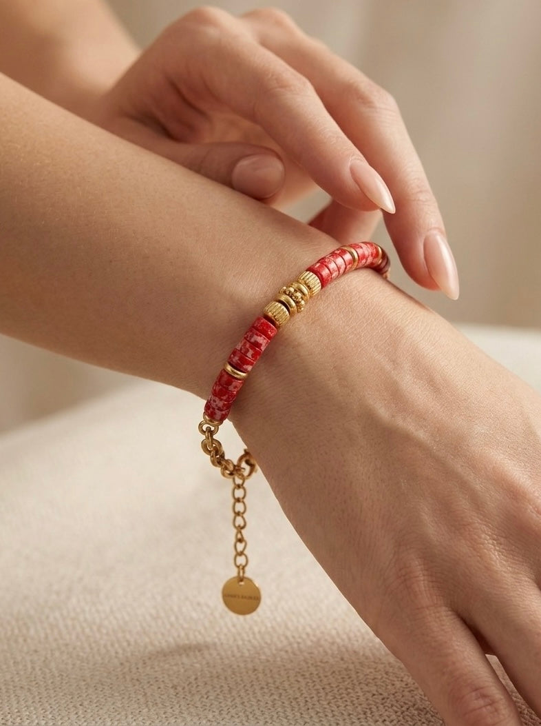 mujer llevando pulsera dorada con cuentas rojas en la muñeca estilo moderno