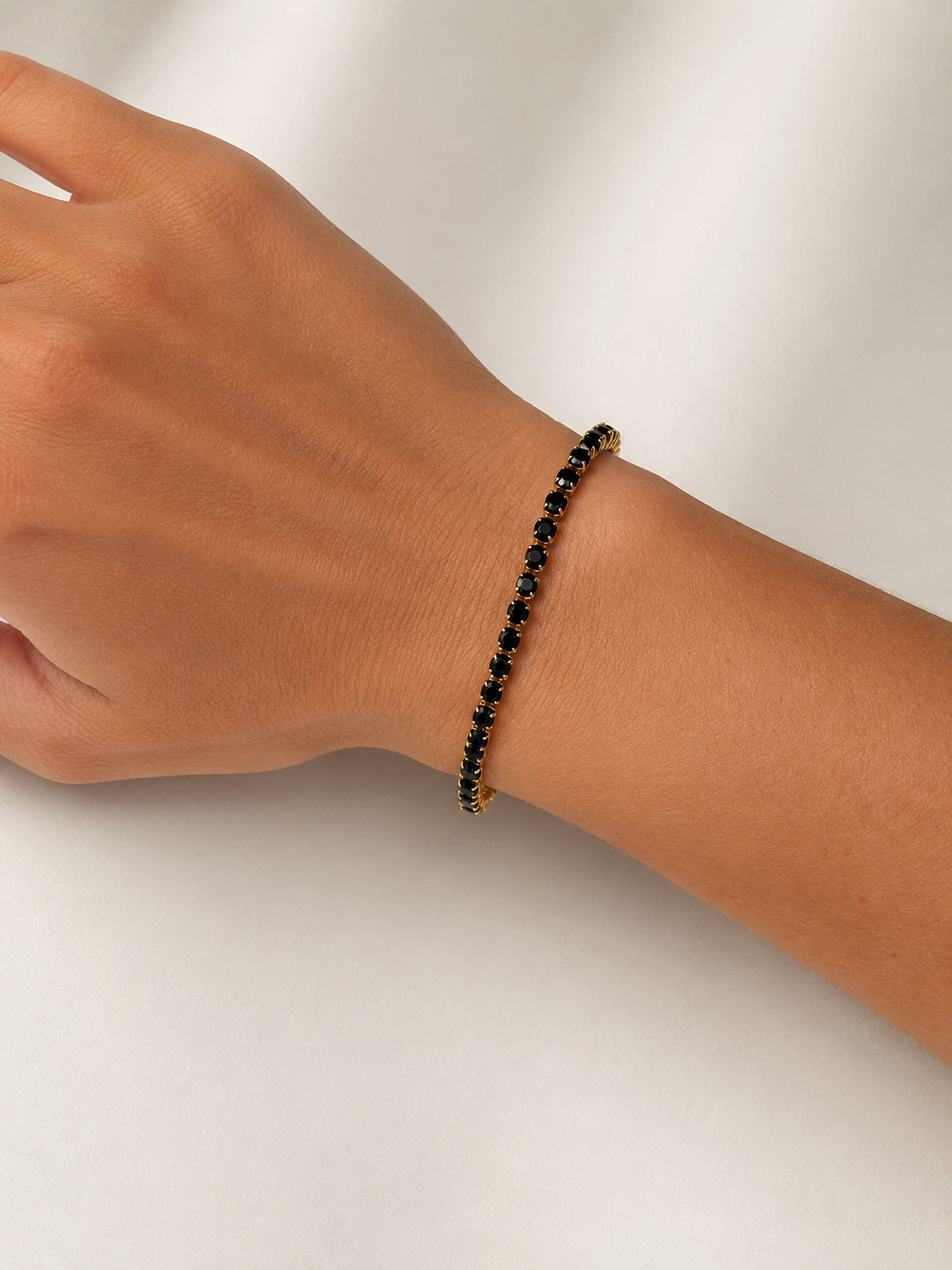 Modelo llevando la Pulsera Ruby dorada con circonitas negras de BRAVATA.