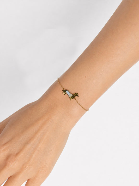 Modelo llevando la Pulsera Tekel dorada con silueta de perro tekel y detalle nacarado blanco de BRAVATA.