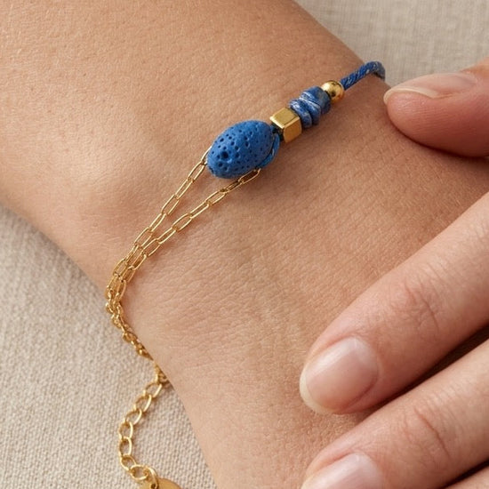 Pulsera con piedra volcánica azul y detalles dorados, llevada en muñeca. Ideal para un estilo natural y actual.
